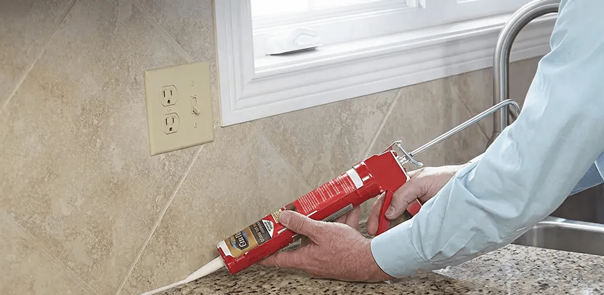 Handyman applying caulk along a kitchen backsplash and countertop seam in Philadelphia, PA